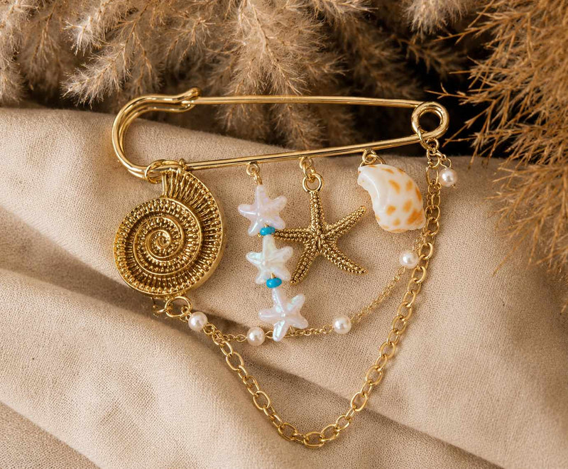 Broche dorado con dijes marinos y perlas