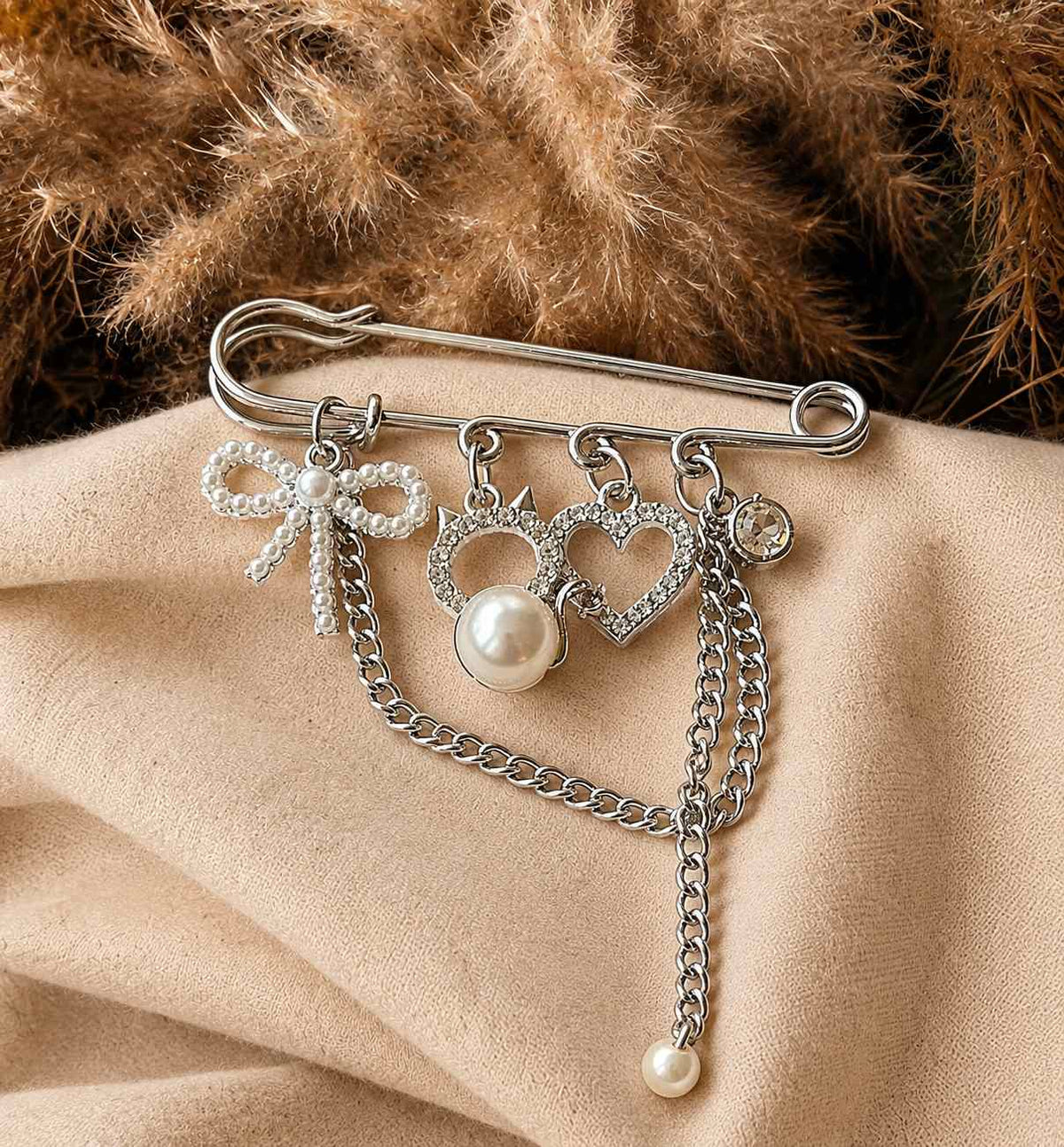 Broche plateado con dijes y perlas
